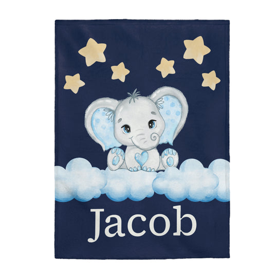 This blanket has a grey elephant with blue ears and a heart in the middle of its chest with blue toes. The elephant is sitting on clouds and stars are above his head. The personalized name is underneath the clouds. The background of the blanket is dark blue.