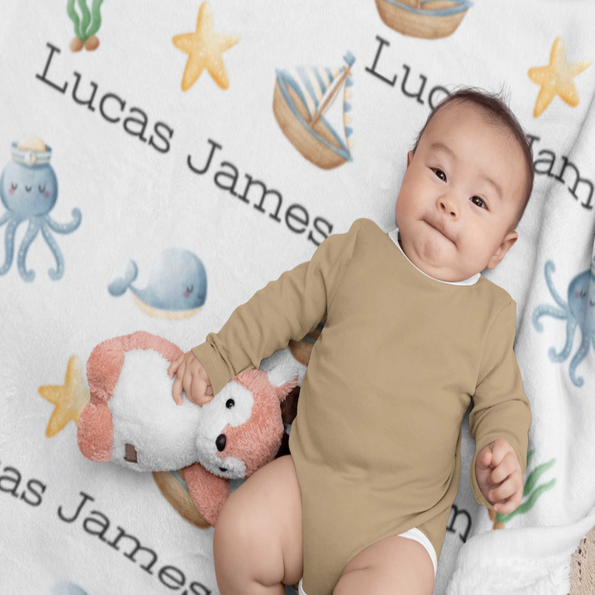  This personalized child's Sea blanket has a baby laying on top of the blanket holding a stuffed animal and wearing a brown onesie. This personalized child's sea blanket has the example name Lucas James spread out six times on the blanket. The blanket has cute whales, octopuses with a cute sailor hat on its head. It has yellow starfish's spread out on the blanket. It has a brown, light blue and yellow ships throughout the blanket. It has green seaweed across the blanket.